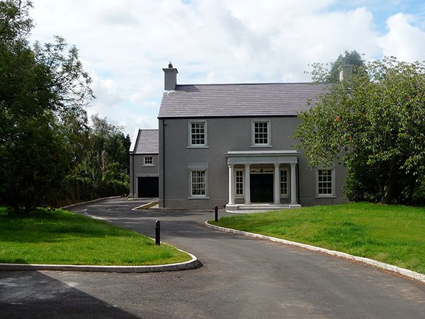 M E Crowe new-build home with rendered facade and portico, County Antrim